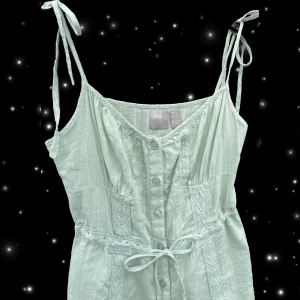 Ljusgrön kort klänning  - Supersöt ljusgrön kort klänning från ASOS med knytbara axelband, knappar framtill och spetsdetaljer. Klänningen har en midja med knytband vilket gör den anpassningsbar ❣️storlek 38 men passar mer en 36. Knappt använd i mycket bra skick