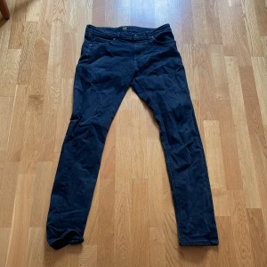 Mörkblå jeans från Lee - Snygga mörkblå jeans från Lee med klassisk femficksdesign och raka ben. Jeansen har Lee-logga på bakfickan och midjan, samt detaljerade sömmar. Perfekt för dig som gillar stilrena och tidlösa jeans med bra passform.
