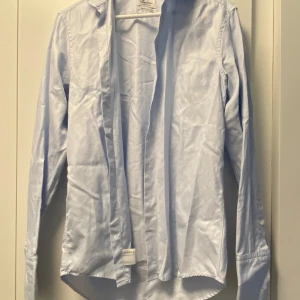 Ljusblå skjorta från Stenströms - Snygg ljusblå skjorta från Stenströms, custom made i tvålagers bomull. Klassisk modell med lång ärm, knappar vid manschetten och krage. Perfekt för dig som gillar stilrena och tidlösa plagg med skön passform.