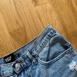 Blå jeansshorts - Snygga blå jeansshorts från 157. Klassisk femficksmodell med knapp och dragkedja. Perfekta för en avslappnad och trendig look under varma dagar.