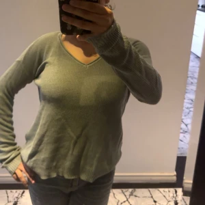 Grön stickad tröja Vero Moda XS - Snygg grön stickad tröja från Vero Moda i storlek XS. Tröjan har v-ringad hals, ribbad struktur och långa ärmar. Perfekt för dig som gillar en chill och enkel stil. Passar till jeans eller kjol och är superbekväm att ha på sig.