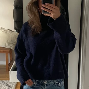 Mörkblå polotröja i ull - Säljer en mörkblå polotröja med hög krage och långärmad modell. Tröjan är stickad i mjuk ull och har en loose passform som ger en chill vibe. Perfekt att matcha med jeans för en enkel och snygg look.