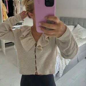 Beige stickad kofta med volangkrage - Superfin beige stickad kofta med stora volanger vid kragen och knappar hela vägen framtill. Storlek M men passar xs/s💓