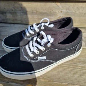 Svarta Vans sneakers med vit sula - Klassiska svarta Vans sneakers med vit sula och vita snören. Skorna har rund tå, tydliga vita sömmar och är tillverkade i canvas. Perfekta för en avslappnad streetstil och passar till det mesta i garderoben.