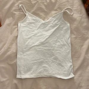 Vit linnetopp i bomull, strl S från Cubus  - Enkel och stilren vit linnetopp från C i storlek S. Toppen har smala axelband och v-ringad hals, 
