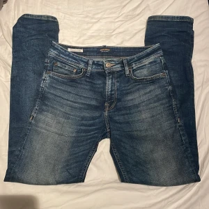 Jack & Jones Regular Clark jeans blå - Snygga blå jeans från Jack & Jones i modellen Regular Clark. Klassisk femficksdesign, raka ben och normal passform. Jeansen har slitningar och ljusare partier framtill. Helt oanvända och skitsnygga!🌟🤩