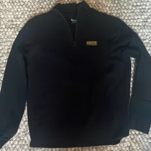 Svart half zip tröja från Barbour - Svart långärmad tröja från Barbour International med half zip. Inköpt 2023 på NK i göteborg. Säljes då jag har vuxit ur den.