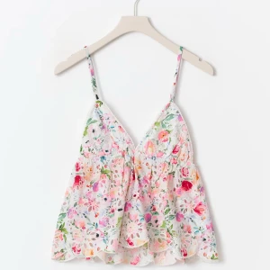 Blommig spetsig linnetopp - Superfin linnetopp med blommigt mönster i pastellfärger och tunna axelband. Toppen har v-ringning och är sydd i ett luftigt spetsmaterial med broderade detaljer. Perfekt för varma dagar och ger en romantisk vibe.