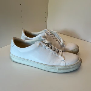 Vita sneakers från Sneaky Steve - Klassiska vita sneakers från Sneaky Steve med rund tå och platt sula. Skorna är i skinn och har snörning framtill. Perfekta för en clean och stilren look, passar till det mesta i garderoben.