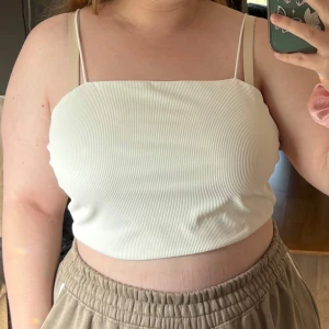 Vit topp - Säljer en stilren vit topp från SHEIN Curve i storlek 2XL. Toppen har tunna axelband och croppad passform, perfekt till höga byxor eller kjol. Materialet är mjukt och stretchigt, vilket gör den superbekväm och enkel att styla.