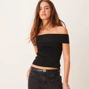 Svart offshoulder topp - Säljer en svart offshoulder topp med ribbad struktur. Toppen har en bred kant upptill som ger en snygg och stilren look. Perfekt att matcha med jeans eller kjol för en trendig outfit.