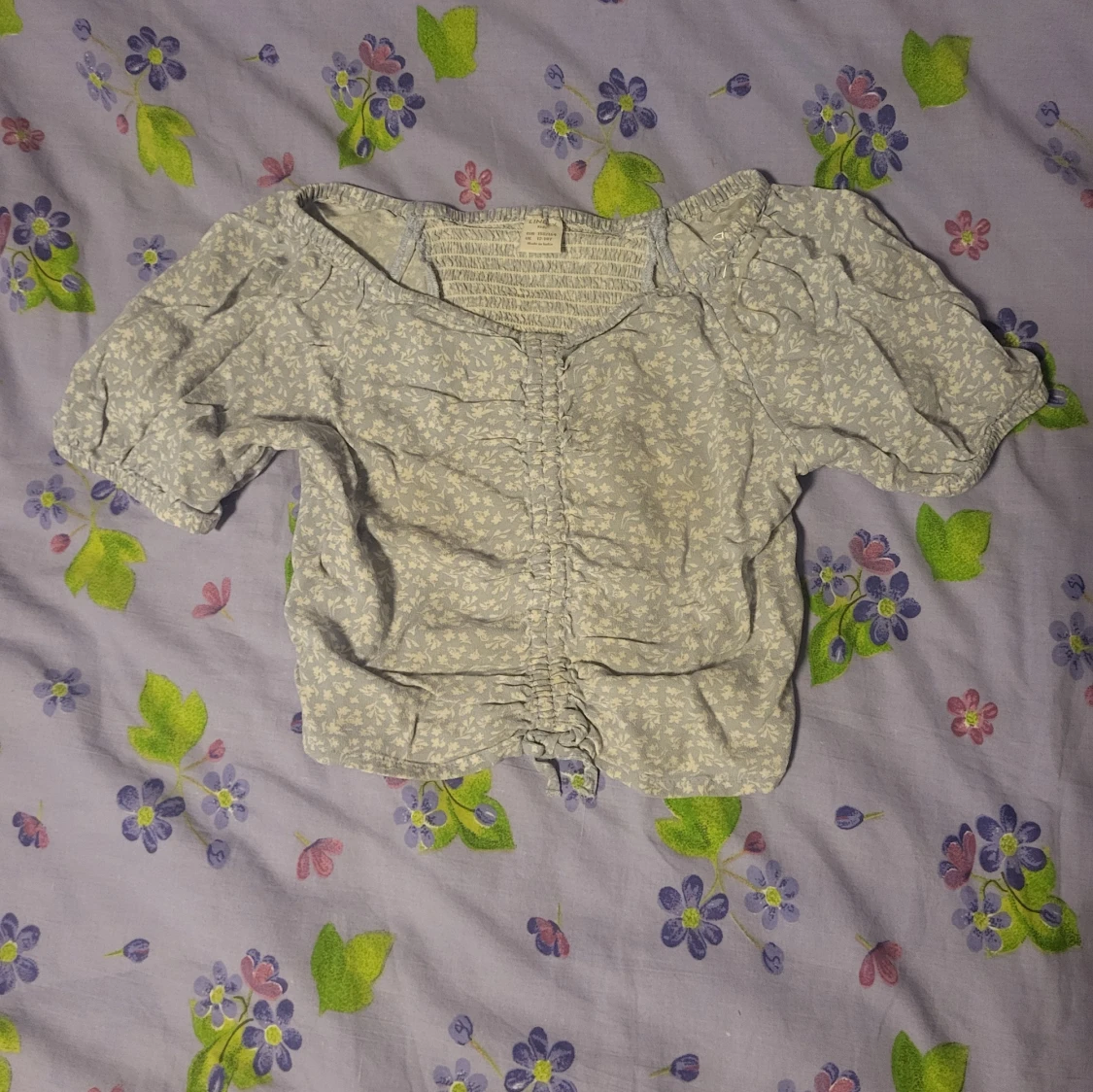 Ljusblå blommig blus med rynkade detaljer