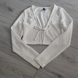 Kort cardigan - Cardigan som är kort i magen men vanlig läng på ärmarna. Rosett knyte och mycket bra skick. Från H&M i storlek xs