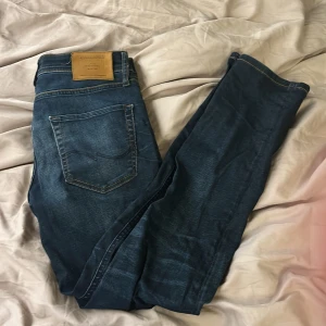 Mörkblå jeans från Jack & Jones - Säljer ett par mörkblå jeans från Jack & Jones strl 29W/30L. De är ett par välanvända jenas men ändå i bra skick. Enda defekten är att på höger och vänster ficka har de tappats lite tyg, se bild 4. Annars är de riktigt fina och i bra skick. Vid frågor så hör gärna av er snabbt svar. Även vid behov av fler bilder så hör av er🙏🏻💯. Pris kan diskuteras. 