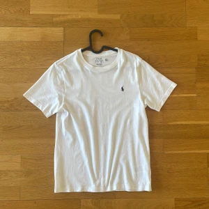 Vit t-shirt från Polo Ralph Lauren - Säljer vit t-shirt från Polo Ralph Lauren med liten broderad logga på bröstet, perfekt för sommaren. Tröjan är i bra skick. Pris kan diskuteras. 