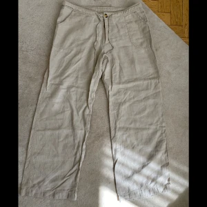 Beiga linnebyxor från Indiska - Säljer ett par beiga linnebyxor från Indiska med breda ben och dragsko i midjan. Byxorna har både fram- och bakfickor och är perfekta för varma dagar 🦒