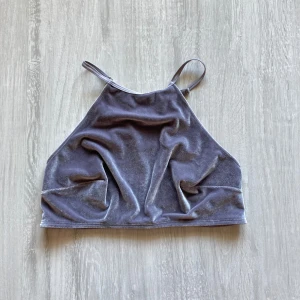 Ljuslila croppad linnetopp från H&M - Säljer en ljuslila croppad linnetopp från H&M med smala axelband. Toppen har en sammetsliknande framsida och baksidan är dekorerad med spetsdetaljer. Perfekt för att addera lite extra stil till din outfit!