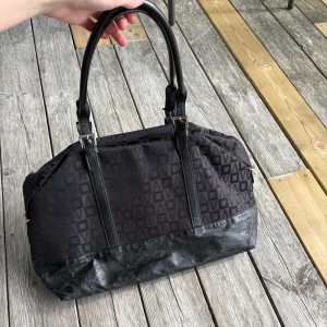 Svart väska - Skit snygg vintage väska från min mamma garderob. Kommer ifrån början av 2000 talet och min mamma har använt den flitigt men dragkedjor och innerfack fungerar som de ska, samt axelbanden. Lite sliten undertill, men oftast inget man ser. Skriv om du har frågor🥰