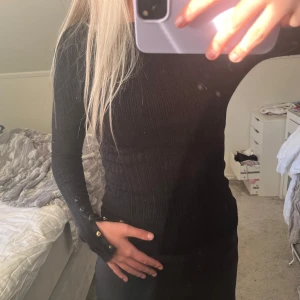 Svart ribbad tröja med knappar från BikBok - Säljer en svart, långärmad ribbad tröja från BikBok i storlek XS. Tröjan har två små hål vid ärmarna! Inget märkbart, men ändå en defekt!💗