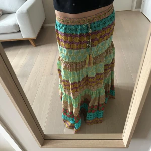 Zara somrig volangklol långkjol strl L (M/L) - Säljer en snygg långkjol i flera färger med blommigt och mönstrat tyg. Kjolen har resår i midjan och dekorativa knytband med snäckor och pärlor. Perfekt för dig som gillar färg och unika detaljer. Fr Zara strl L men passar även på M. 