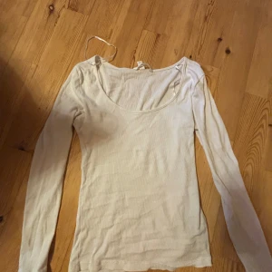 Vit ribbad långärmad topp från H&M - Säljer en enkel och stilren vit långärmad topp från H&M. Tröjan är ribbad och har en rundad halsringning, perfekt att matcha med jeans eller kjol. Materialet är mjukt och stretchigt för en bekväm passform.