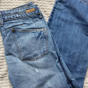 Blå jeans från MNGjeans - Säljer ett par klassiska blå jeans från MNGjeans med normal passform. Med dubbla knappar i midjan och snygga detaljer i guldmetall. Lite baggy och låg i midjan.