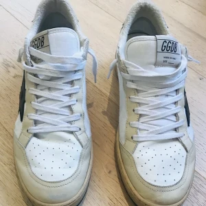  Golden Goose | feta | byte - Säljer ett par vita sneakers från Golden Goose med svart stjärna på sidan och beige detaljer. Skorna har snörning, perforerad tå och en klassisk låg modell. Perfekta för dig som gillar streetstyle | kan bytas mot förslag , ingen låda eller kvitto