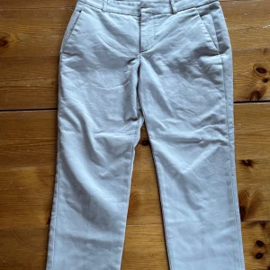 Beige kostymbyxor från ZARA - Snygga beige kostymbyxor från ZARA med klassisk passform och raka ben. Byxorna har fickor fram och dekorativa fickor bak. Perfekta för en stilren look och tillverkade i ett lätt material.