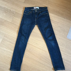 Levi's 512 Slim Taper jeans blå - Säljer ett par klassiska blå Levi's 512 Slim Taper jeans. De har fem fickor, dragkedja och knapp i midjan samt snygga kontrastsömmar. Perfekta för dig som gillar en smalare passform med avsmalnande ben.
