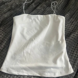 Vit linnetopp från Amisu - Säljer en enkel och stilren vit linnetopp från Amisu med tunna axelband. Perfekt för varma dagar eller som layering-plagg. Toppens material känns mjukt och lätt mot huden.