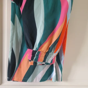 Färgglad byxor med vågigt mönster från SHEIN - Säljer en färgglad byxor från SHEIN i storlek L med vågigt mönster i grönt, rosa, orange, svart och vitt. Byxor har resår i midjan och är tillverkad i ett lätt och bekvämt material. Perfekt för dig som gillar färg och mönster!