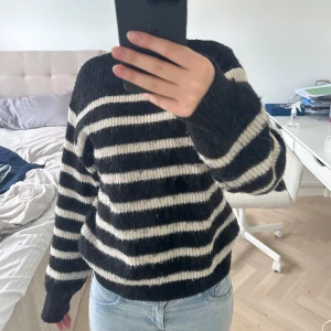 Svart och vit randig stickad tröja från H&M - Mysig stickad tröja från H&M i svart och vitt med breda horisontella ränder. Tröjan har lång ärm, rund halsringning och ribbade muddar vid ärmslut och nederkant. Perfekt för kyligare dagar.💞