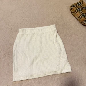 Vit ribbad kortkjol från SHEIN - Säljer en vit ribbad kortkjol från SHEIN i storlek XS. Kjolen har en enkel och stilren design med resår i midjan och är perfekt för en fräsch och avslappnad look.