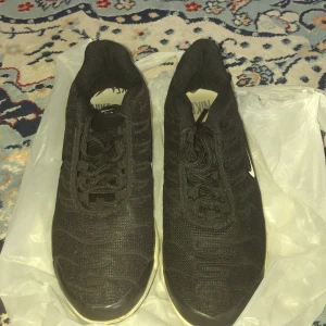 Svarta Nike Air Max sneakers - Säljer ett par svarta Nike Air Max sneakers med vit sula och diskret vit swoosh på sidan. Skorna har snörning och en synlig luftbubbla i sulan för extra komfort. Perfekta för dig som gillar sportig stil.