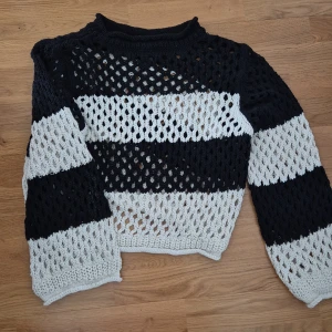 Hålstickad tröja från Lindex - svartvit - Säljer en svart och vit stickad tröja från Lindex med breda ränder och hålmönster. Tröjan har lång ärm och är croppad i modellen. Endast provad.