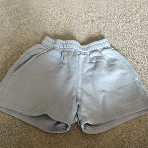 Ljusblå shorts från Peak Performance  - Ljusgrå shorts från Peak Performance med elastisk midja och sidofickor. Mjukt material och diskret broderad logga framtill. Perfekta för en avslappnad stil.