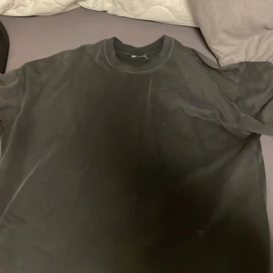 Svart t-shirt från Zara - En klassisk Black t-shirt Washed effect  från Zara med rund halsringning. Enkel och stilren design utan tryck eller mönster, perfekt till många olika outfits. Tillverkad i mjukt material! Orginal pris 500kr men säljer för 100!
