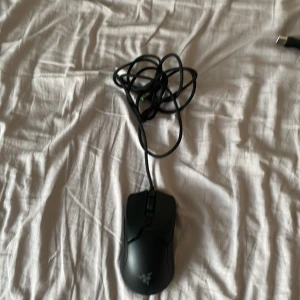 Svart gamingmus från Razer - Säljer en svart trådbunden gamingmus från Razer med klassisk ergonomisk form och logotyp på ovansidan. Musen har flera knappar och lång USB-kabel, perfekt för gaming eller arbete vid datorn.