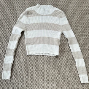 Beige och vit randig croppad tröja - Fin croppad, ribbad tröja med breda beige och vita ränder i storlek S! Köpt på en nedlagd sida, står Trendyol på lappen. 