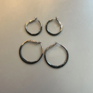 Två par silvriga/svarta hoops örhängen - Säljer två par klassiska hoops örhängen i silver/svart färg. Ena paret är större och det andra är lite mindre.