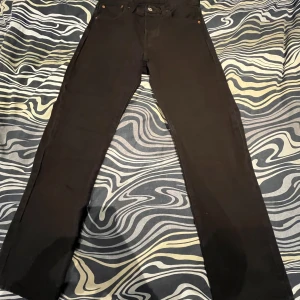 Svarta jeansbyxor från Levi's - Säljer ett par svarta jeansbyxor från Levi's med klassisk femficksdesign och raka ben. Byxorna har knappgylf och läderpatch bak i midjan. Perfekta för dig som gillar en tidlös och clean look. Levis 501. Storlek 28/32 men är uppsatta så skulle säga 28/30. Pris kan diskuteras