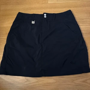 Svart kjol från Röhnisch - Svart kjol från Röhnisch med två silverfärgade knappar framtill och diskret logga. Kjolen är i storlek S och i fint skick! 