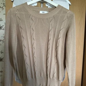 Beige stickad tröja från Noa Noa - Säljer en beige stickad tröja från Noa Noa med diskret mönster längs framsidan. Tröjan har rund halsringning och långa ärmar. Perfekt för lager-på-lager och passar till många olika stilar.