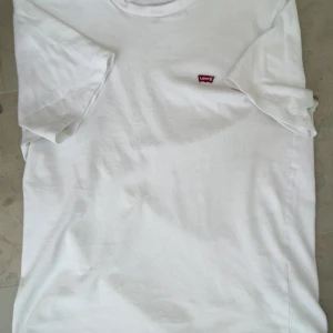 Klassisk Vit t-shirt från Levi's - Klassisk vit t-shirt från Levi's med liten röd logotyp på bröstet. Enkel och stilren design med rund hals och korta ärmar. Perfekt basplagg till garderoben. En MUSTHAVE nu inför sommaren.                                                              Kan slängas med gratis vid bundle med två andra varor!   Skriv vid minsta fundering! Alla frågor är välkomnade!      Nypris ~599kr