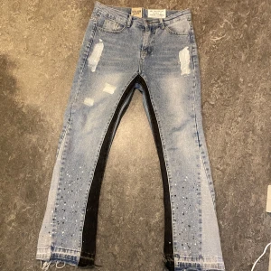 Gallery Dept. La Flare jeans - Unika ljusblå jeans från Gallery Dept. med slitningar, svarta paneler längs insidan av benen och handgjorda målningar. Klassisk femficksmodell med råa kanter vid benslut. Design av Josué Thomas. Storlek M, men passar som S.