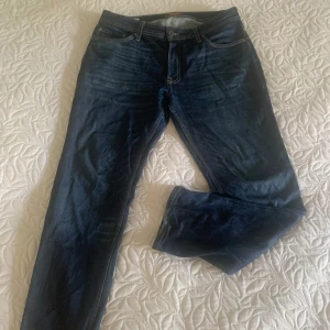 Jack and Jones  - Säljer ett par mörkblå jeans från Jack & Jones, modell Regular Clark. Klassisk femficksdesign med raka ben och normal passform. Snygga kontrastsömmar och traditionell jeanslook. Perfekta för dig som gillar enkel och tidlös stil. Ny skick. Köpt för 799. 