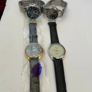 Fyra herrklockor f - Säljer fyra stilrena herrklockor, två med svart urtavla och metallarmband, en med svart urtavla och guldfärgad boett samt svart läderarmband, och en med vit urtavla och svart läderarmband. Perfekta accessoarer för att lyfta din stil. Helt nya saknar endast batterier 