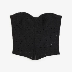 Svart spetskorsett - Säljer en svart korsett-topp med spetsdetaljer och broderat mönster. Toppen är axelbandslös och har en figurnära passform som framhäver midjan. Perfekt att styla till både jeans och kjol för en trendig look.