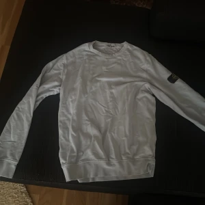 Jus blå sweatshirt från Stone Island Junior - Säljer en stilren vit sweatshirt från Stone Island Junior. Tröjan har rund halsringning, långa ärmar och klassisk patch på ena ärmen. Perfekt för en clean och enkel look.