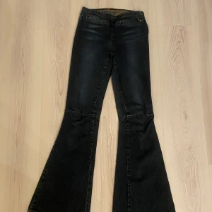 Svarta bootcut jeans med dragkedja - Säljer ett par svarta bootcut jeans med dragkedja. Jeansen har en markerad utsvängd passform nertill och kontrastsömmar. Perfekta för dig som gillar retrostil och vill sticka ut.